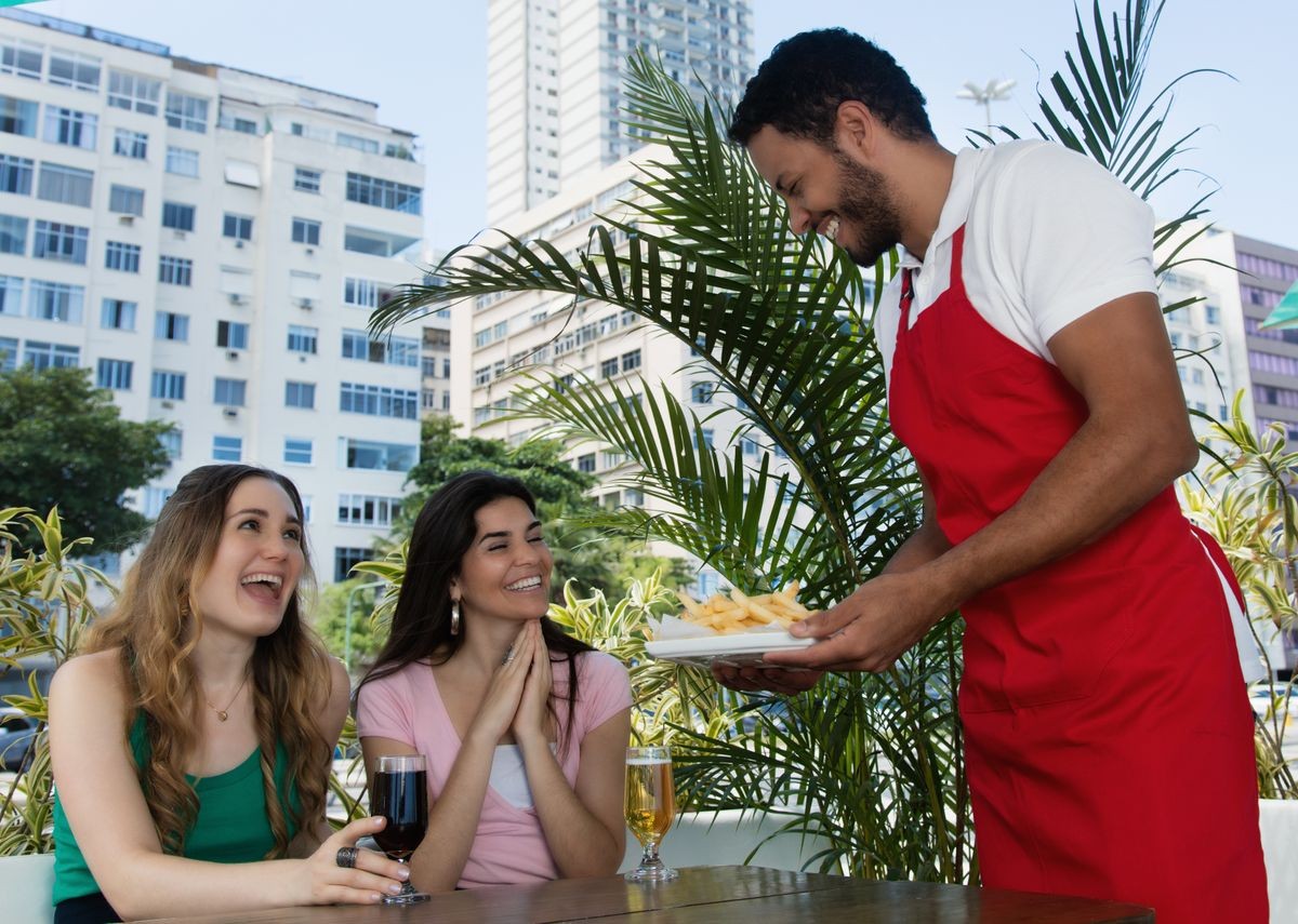 Male waiter serving french fries to guests in a restaurant